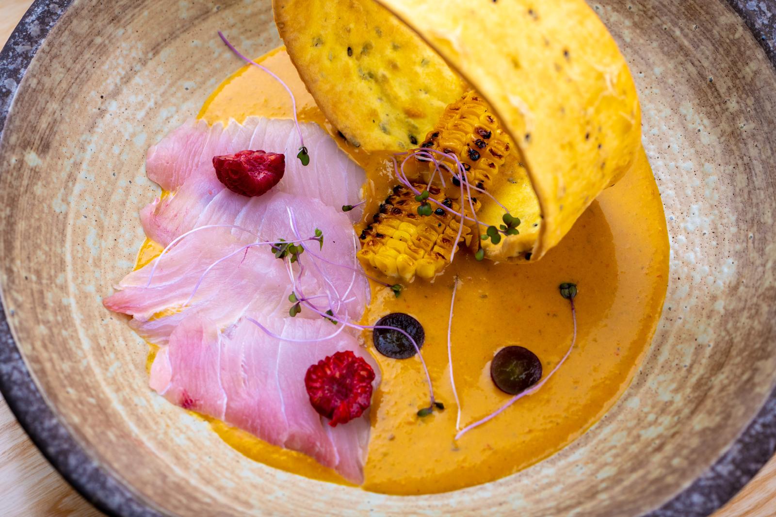 Gourmet dish with fish, grilled corn, and microgreens